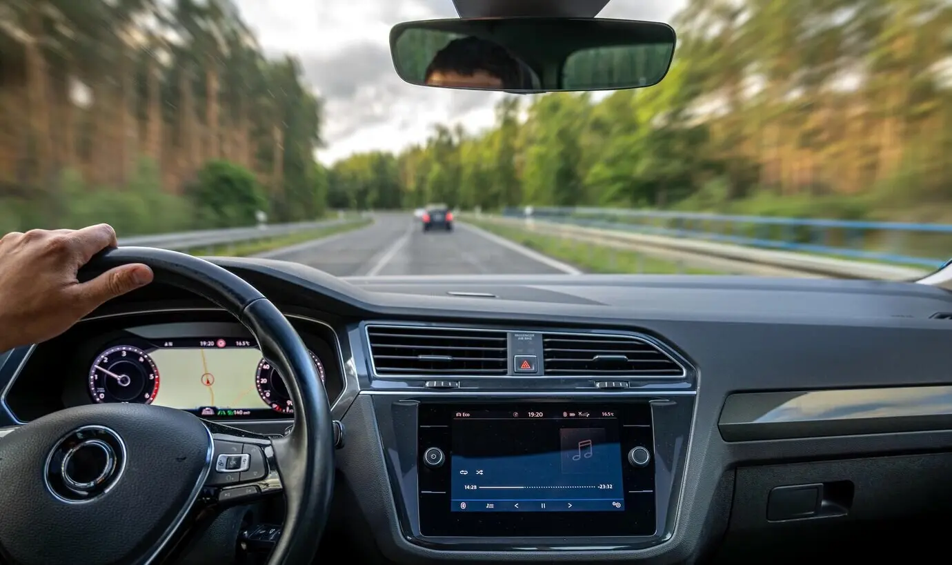 Hand des Fahrers am Lenkrad, Waldstraße, Geschwindigkeit und Unschärfeeffekt