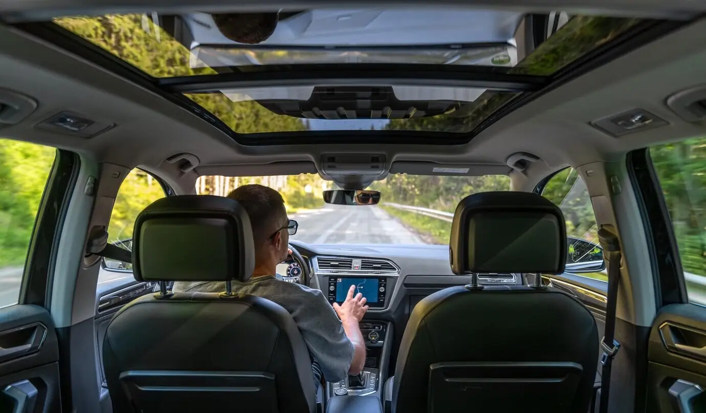 Autofahrt mit Navigation und Panoramadach, ein Mann fährt das Fahrzeug.